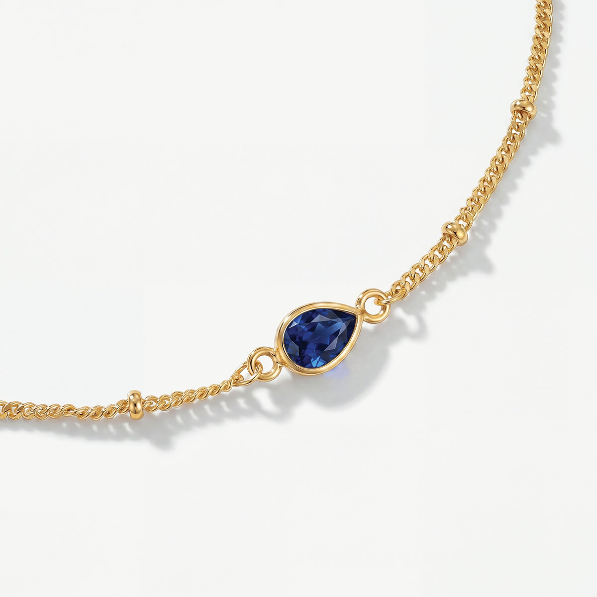 Genuine enhanced sapphire teardrop gemstone on 18ct gold plated birthstone bracelet